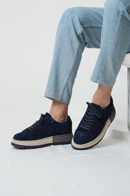 Navy blue sneakers worn with light blue jeans on a white background