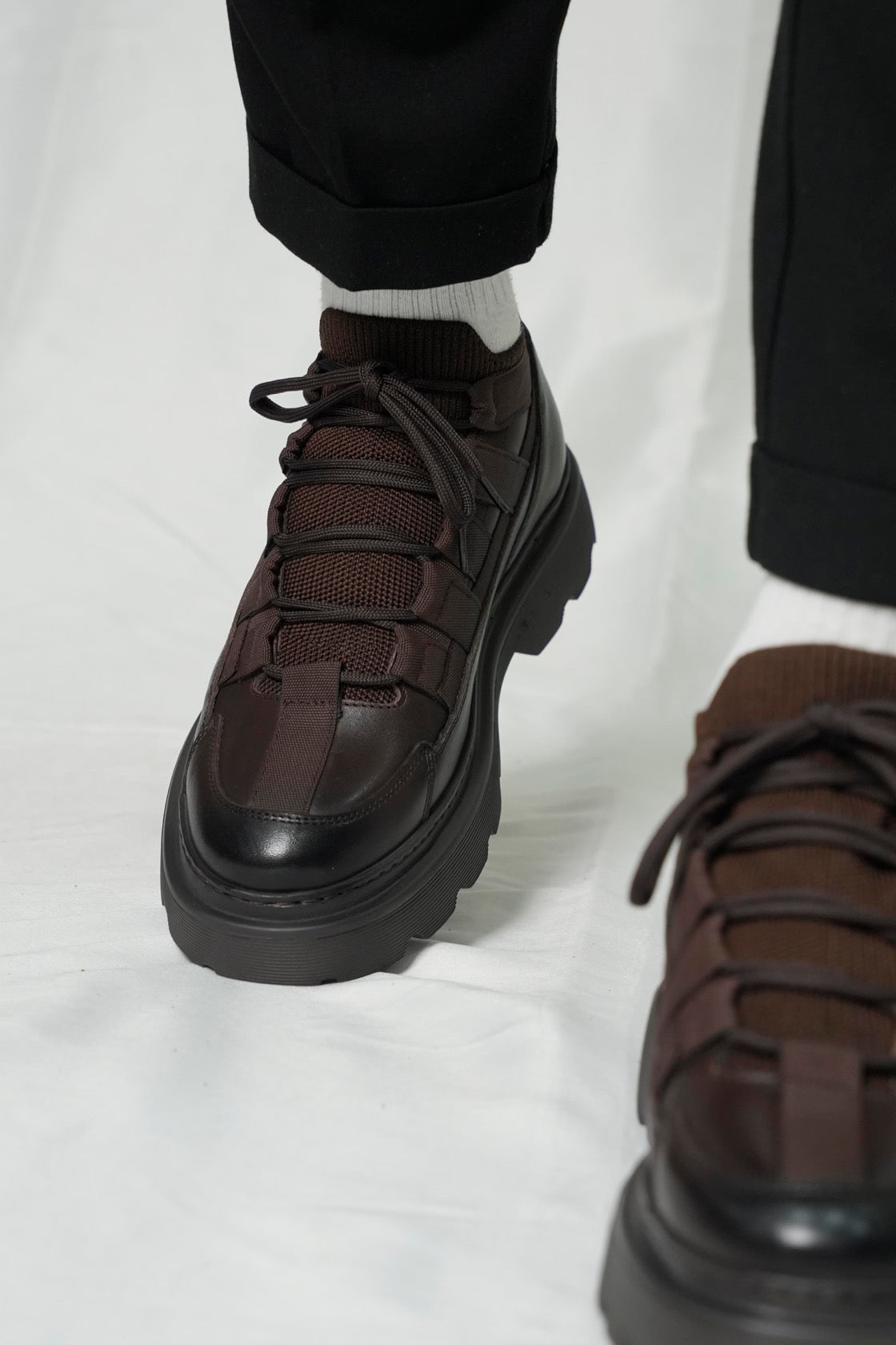 Brown platform shoes worn with black pants on a white background